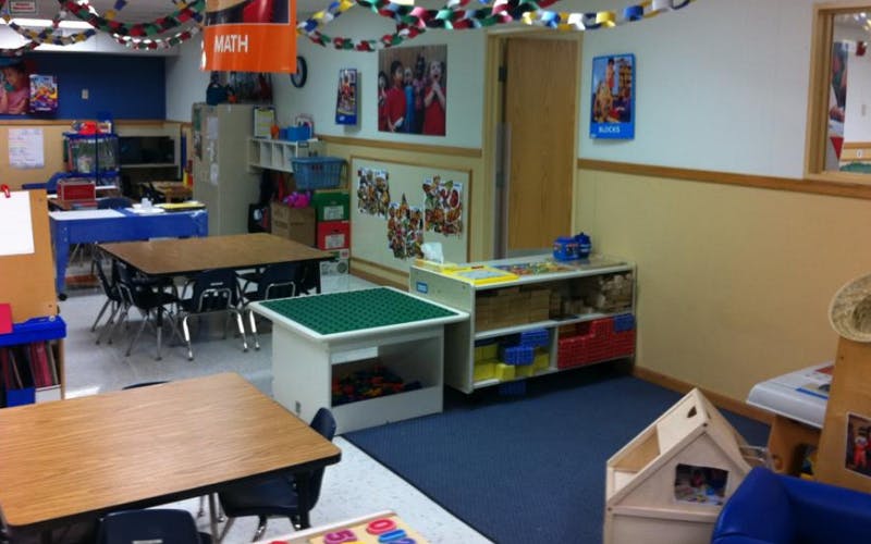 Classroom with tables, chairs, and shelves full of learning materials
