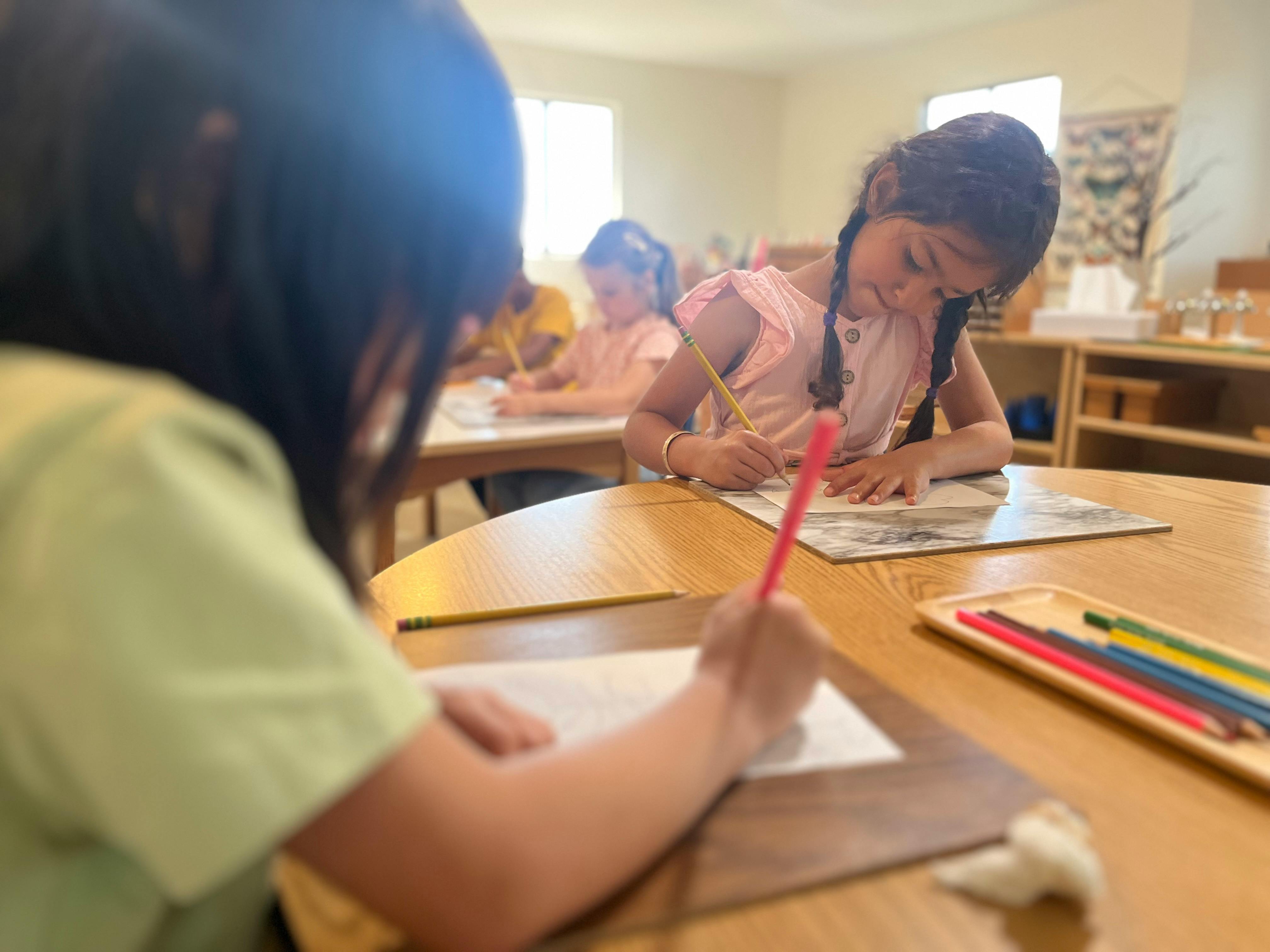 Children drawing and writing at desks in a classroom