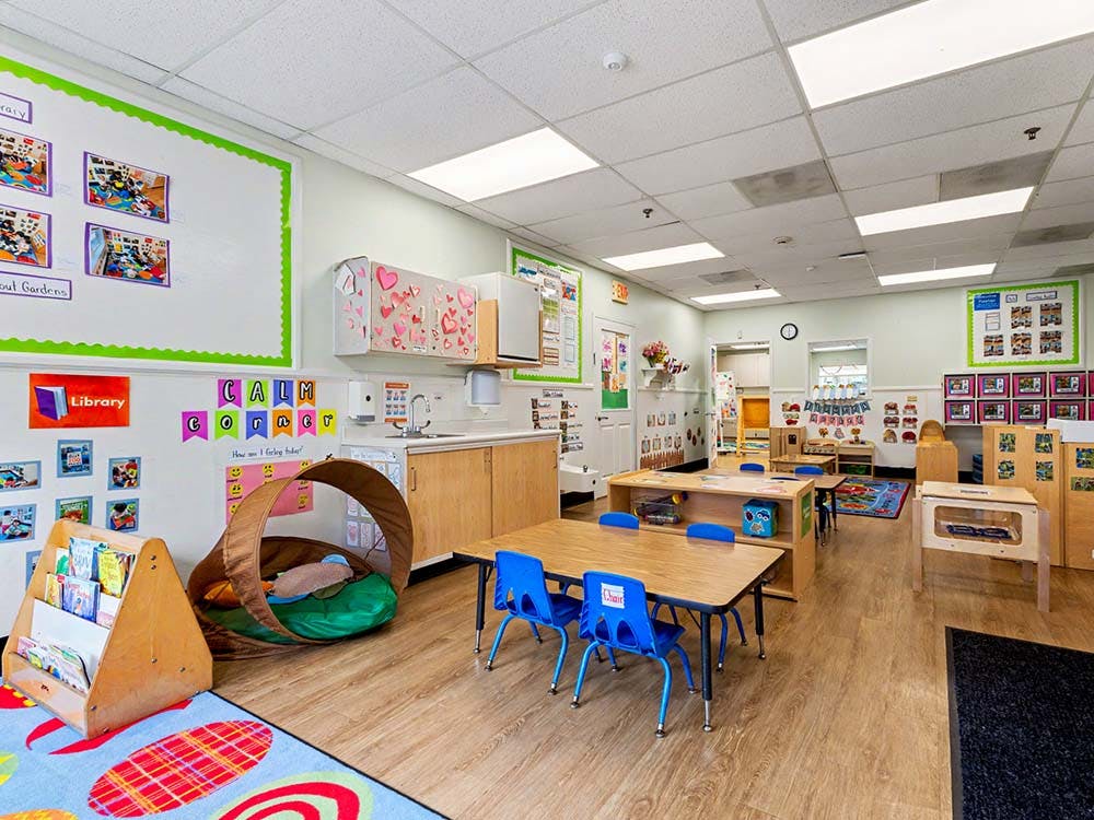 Classroom with small tables and chairs, a sink, and a reading nook