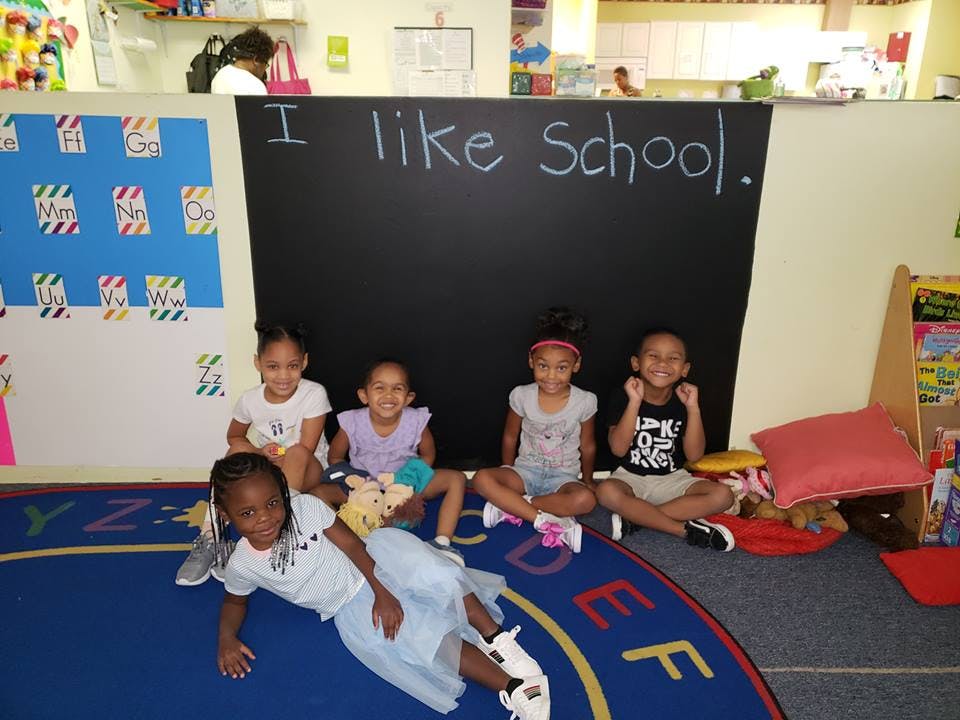 Five children in a classroom with "I like School." written on a blackboard