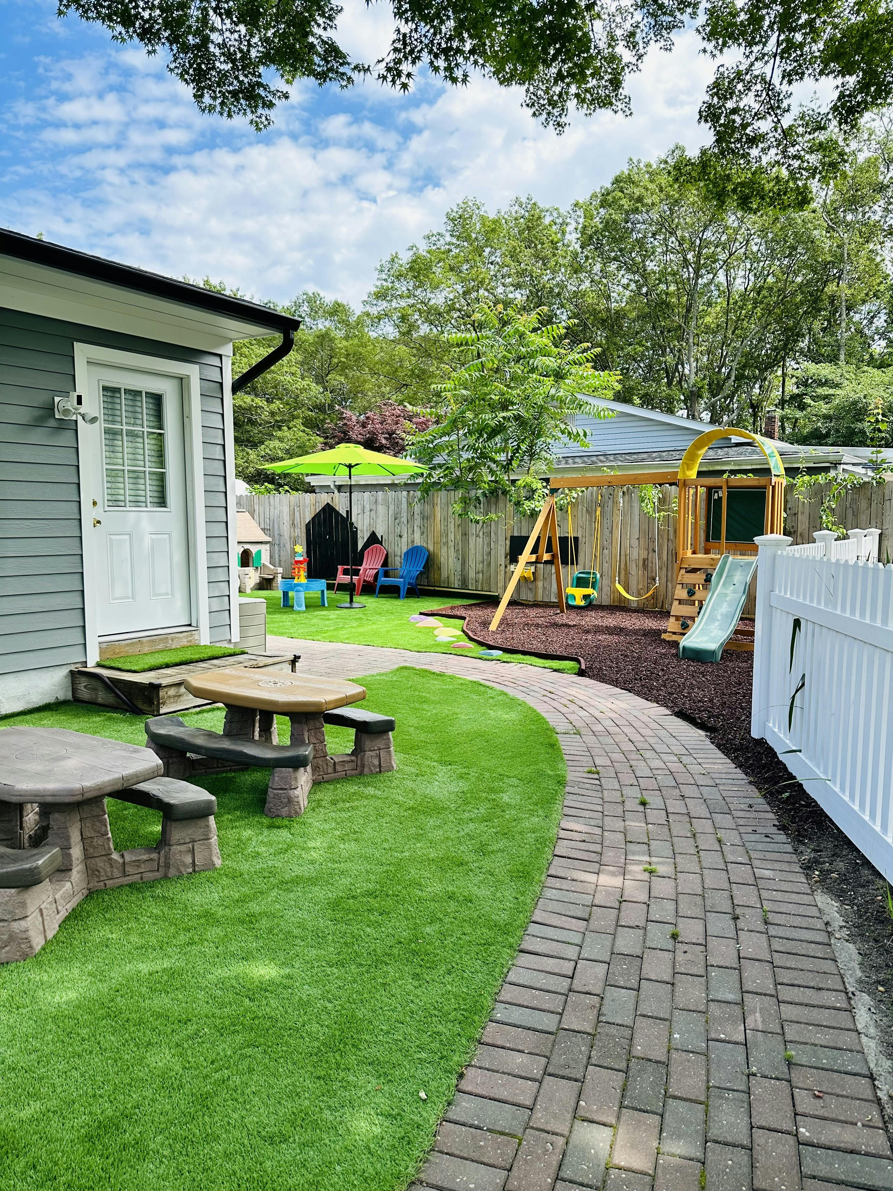 Backyard with a swing set, slide, and picnic tables