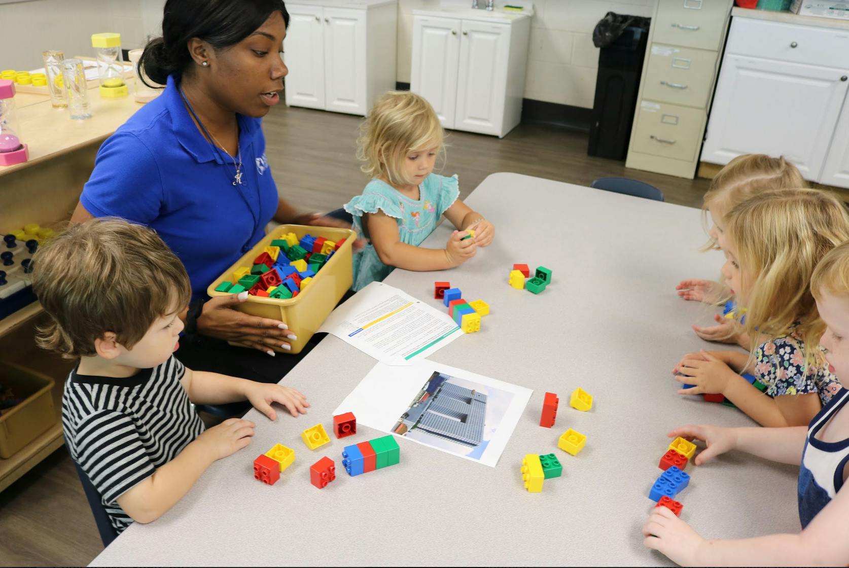 Adult and children playing with colorful building blocks at a table