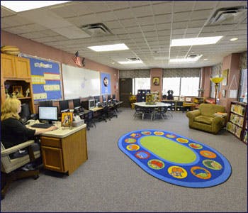 Person at computer in a classroom with a colorful rug