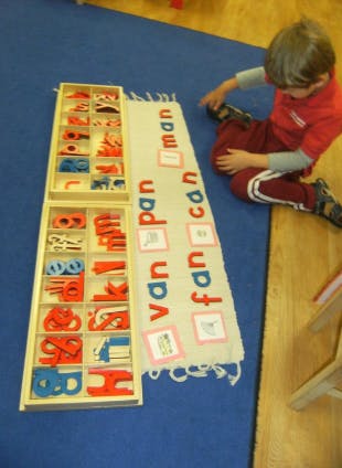Child on floor with alphabet letters and word strips
