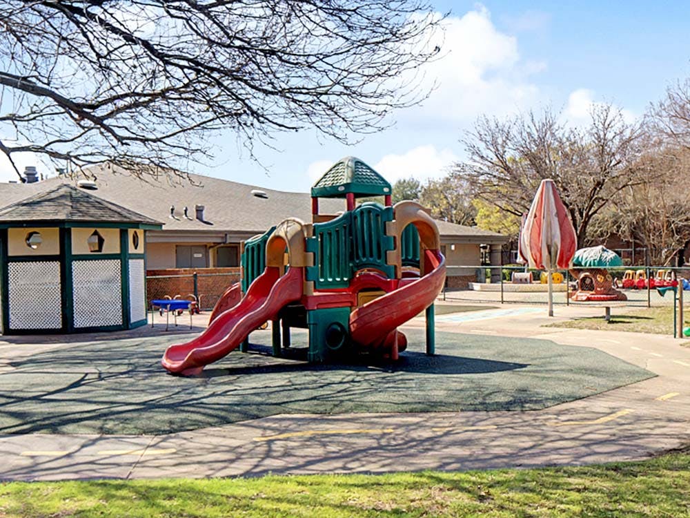 Empty outdoor playground with colorful play structure and green ground