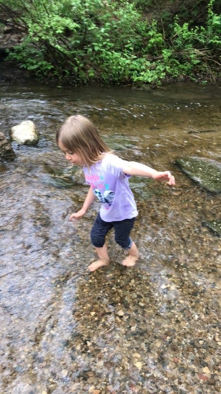 Child walking barefoot in a shallow stream