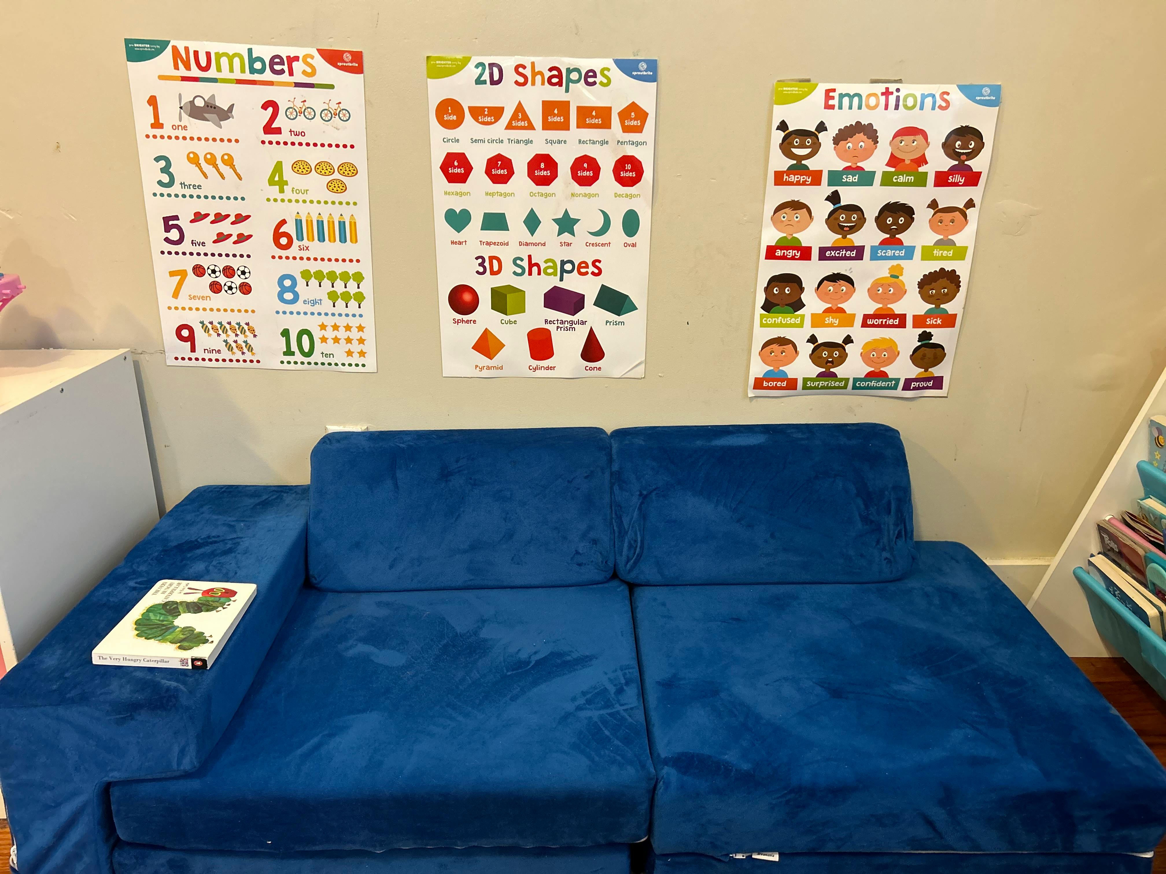 Blue modular sofa with educational posters on the wall above it is a classroom