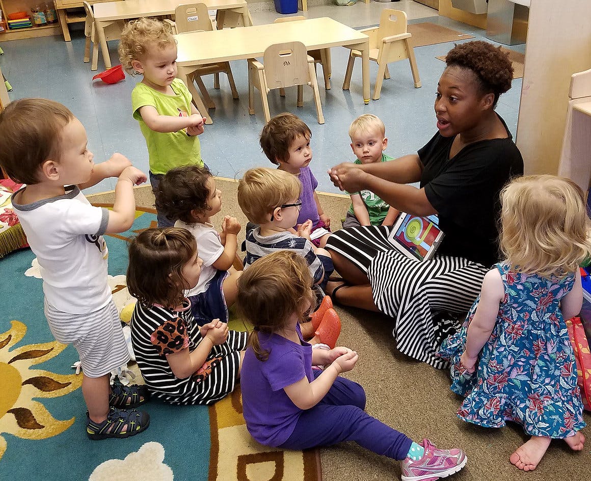 Person reading to a group of children in a classroom