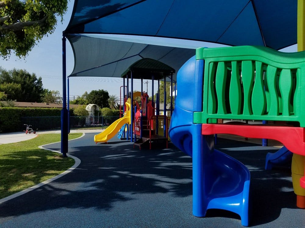 Playground with slides and climbing structures under a shade canopy