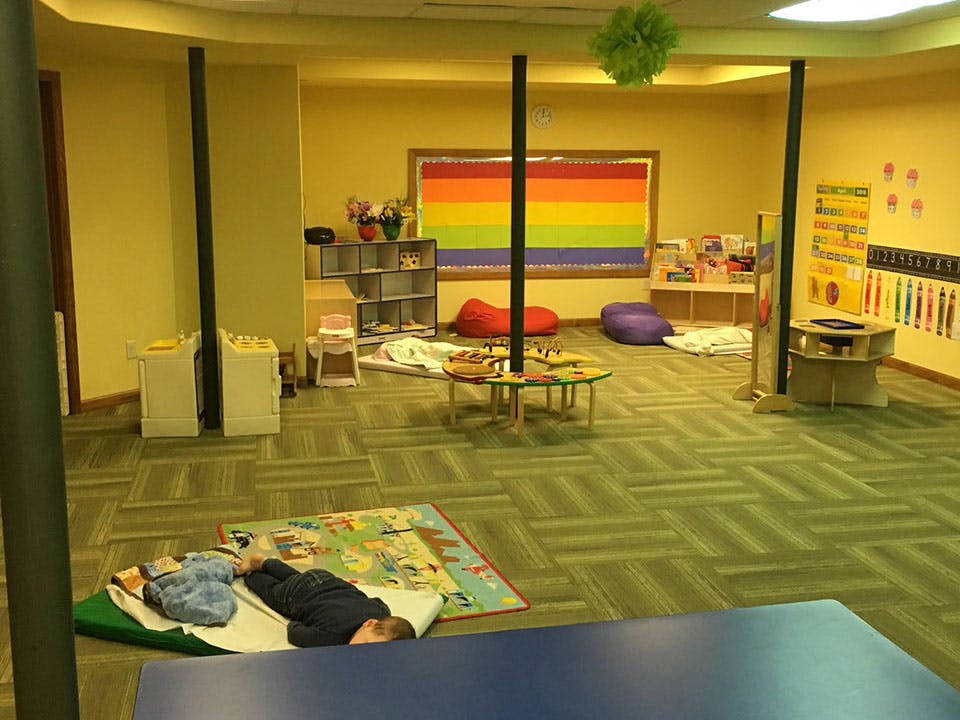 Child sleeping on a mat in a classroom