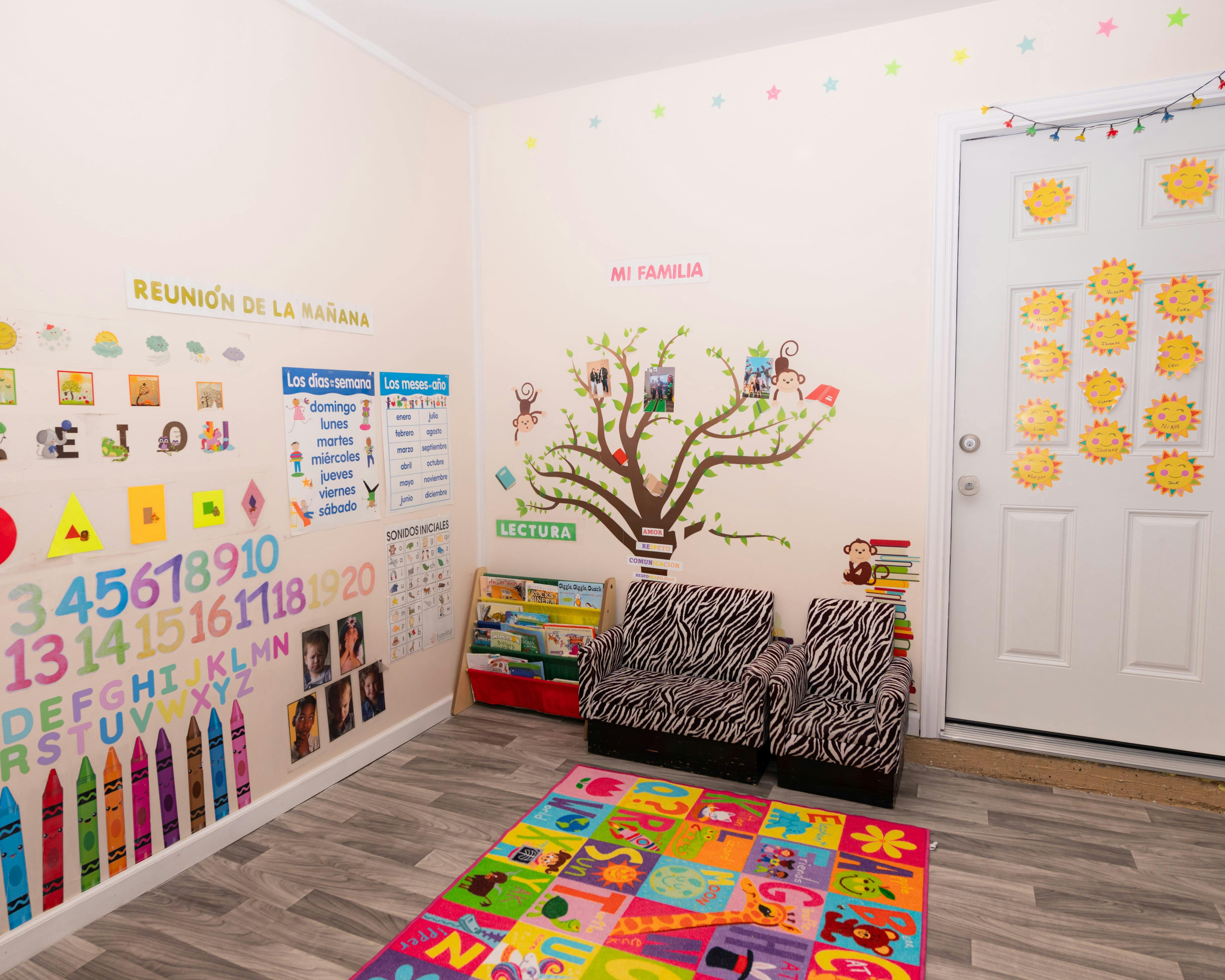 Classroom with colorful wall decorations, small chairs, and a play rug