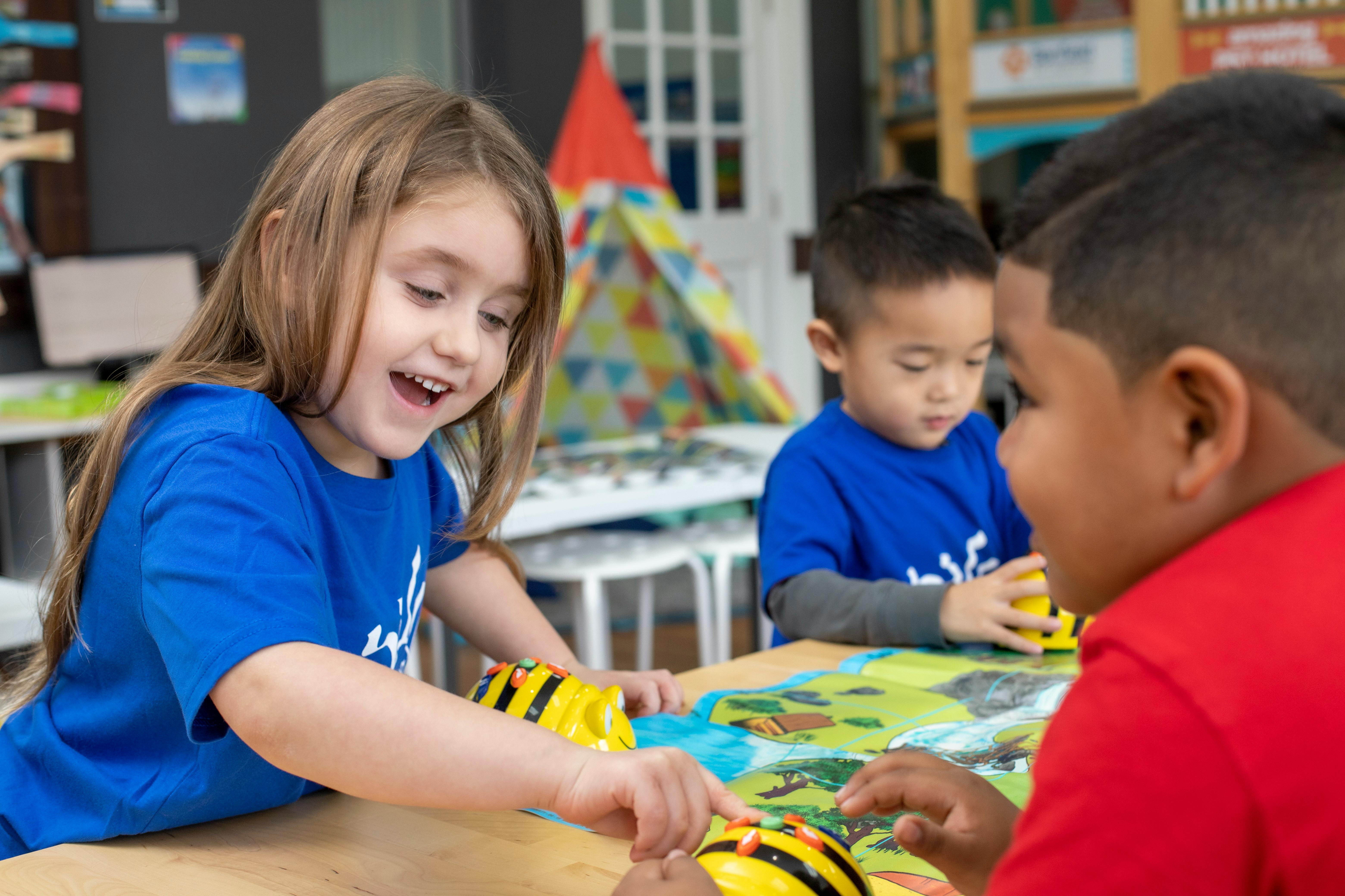 Child in blue shirt playing with a bee toy with other children