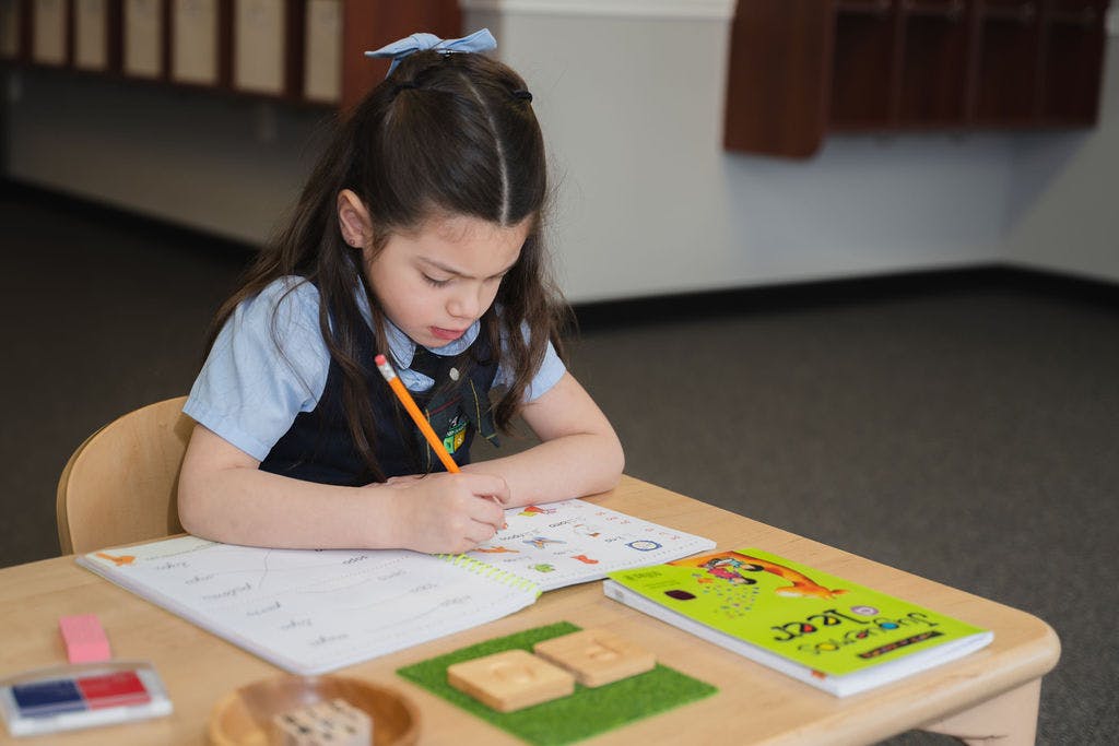 Child writing in a workbook at a desk