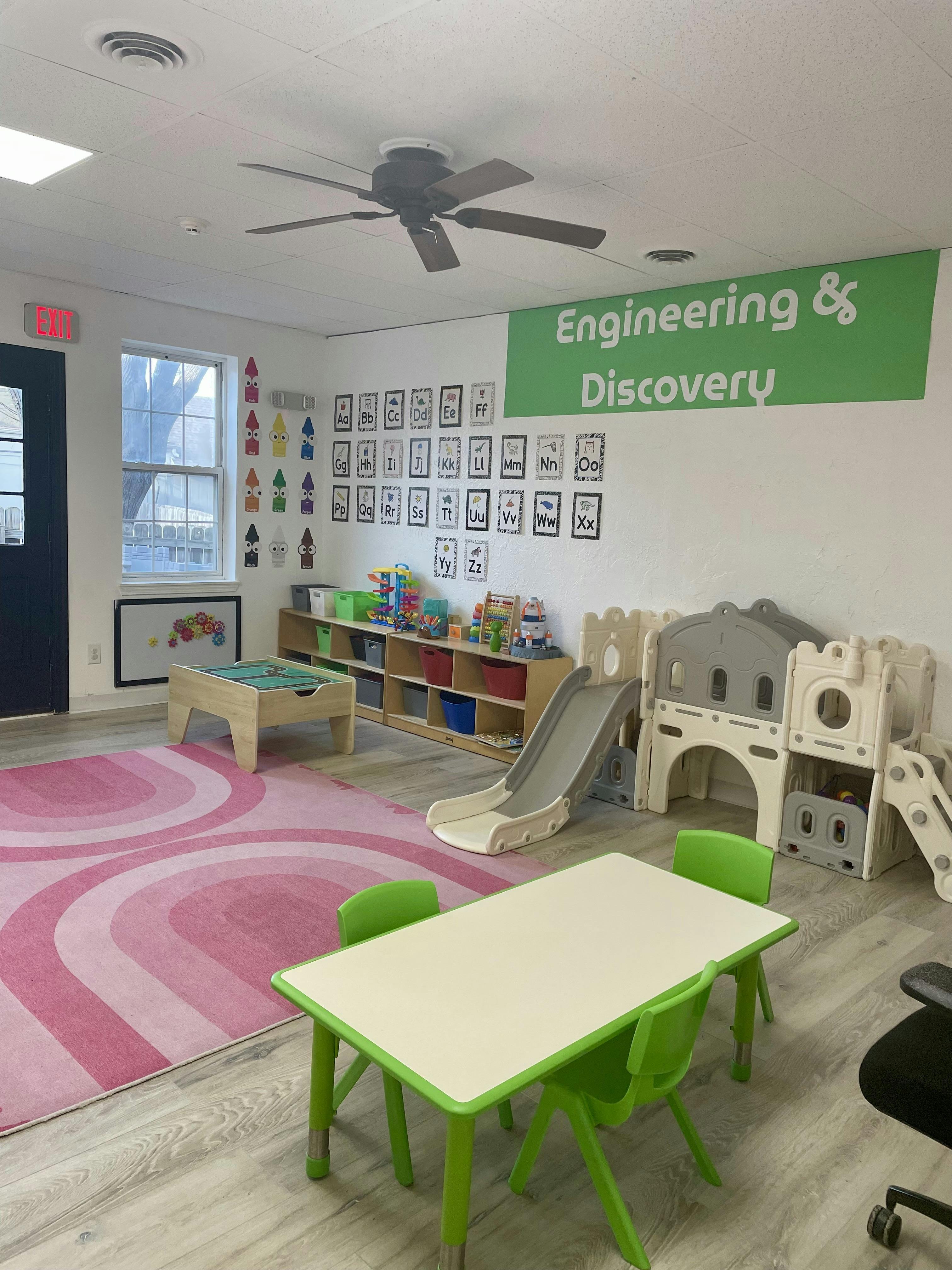 Classroom with toy slides, small tables, and alphabet wall displays