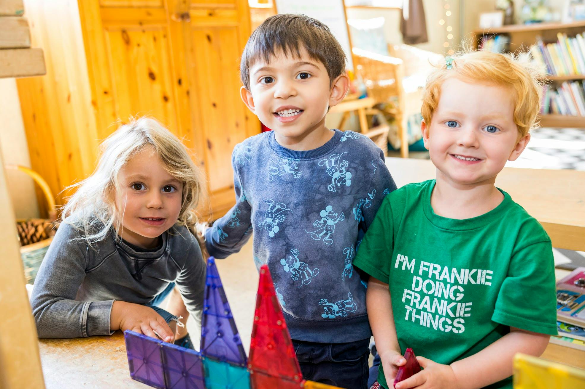 Three children playing with colorful magnetic tiles