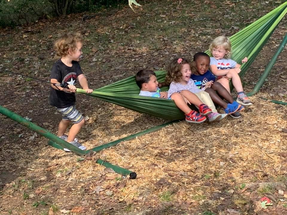 Children playing in a green hammock outdoors