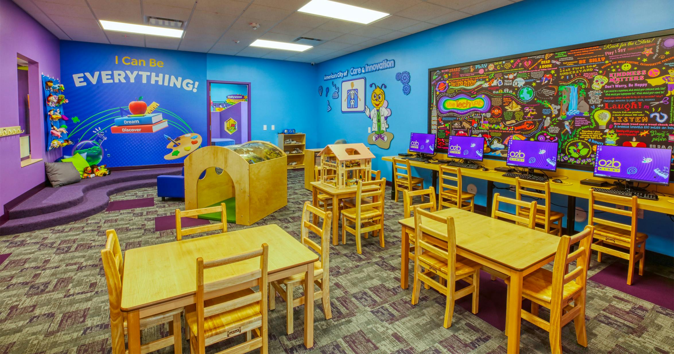 Colorful children's classroom with computers, activity tables, and a reading nook