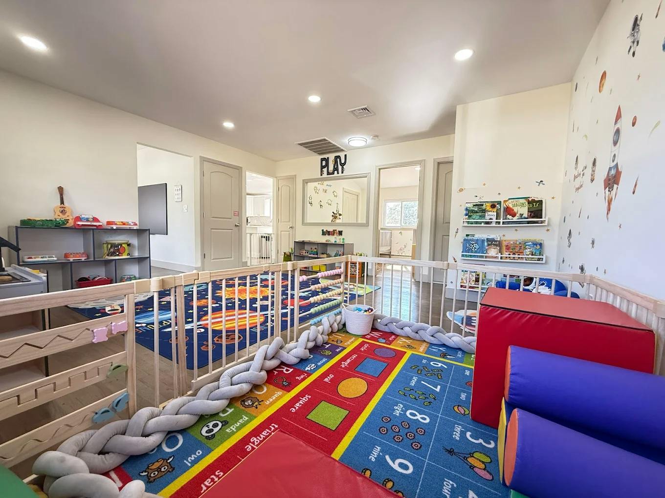 Indoor play area with colorful mats, soft play equipment, and a gate