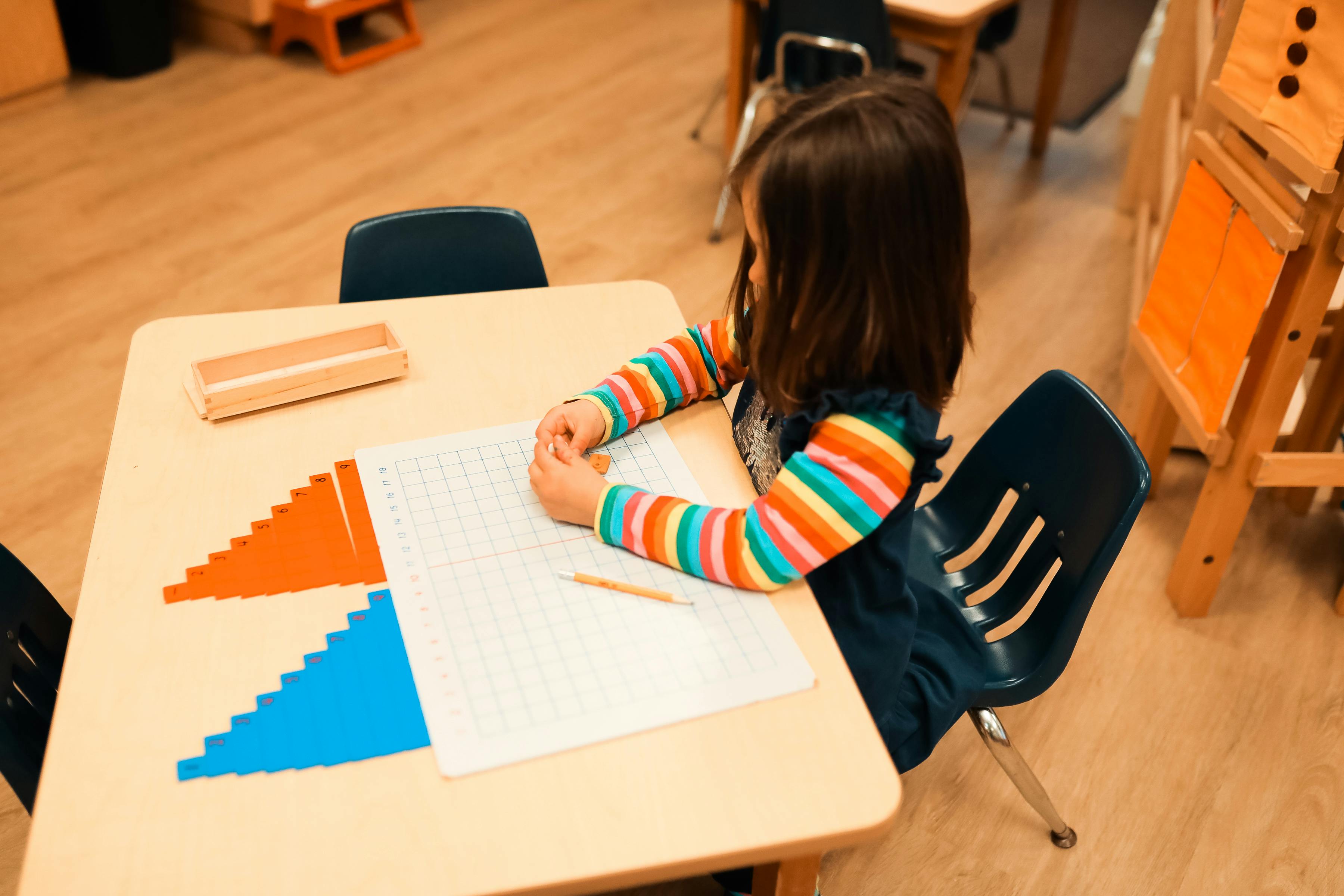 Child at a desk with paper and geometric shapes