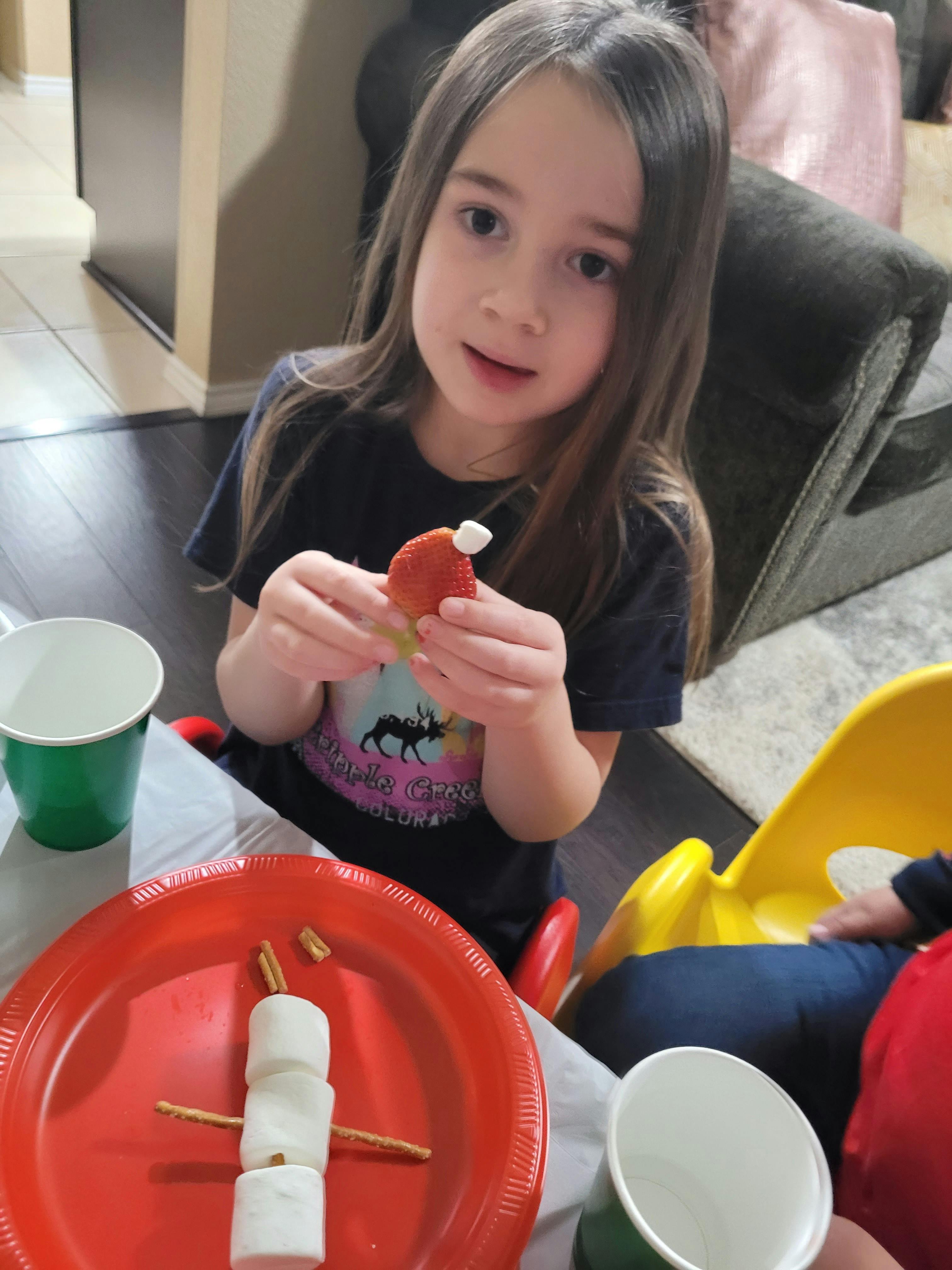 Child holding a small red object with a white top, fluffy top
