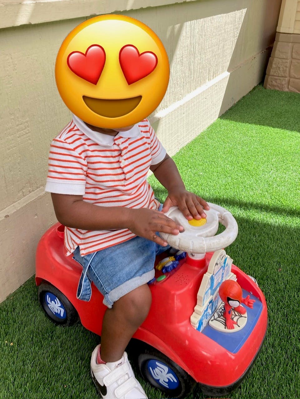Child sitting on a red toy car