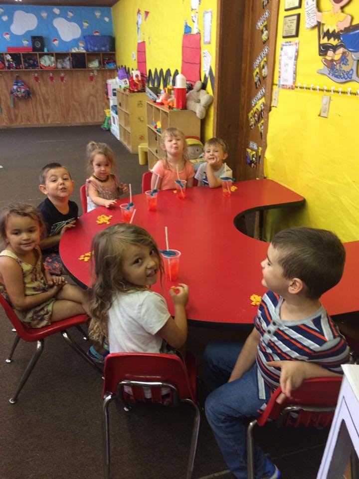 Children sitting around a red table in a classroom
