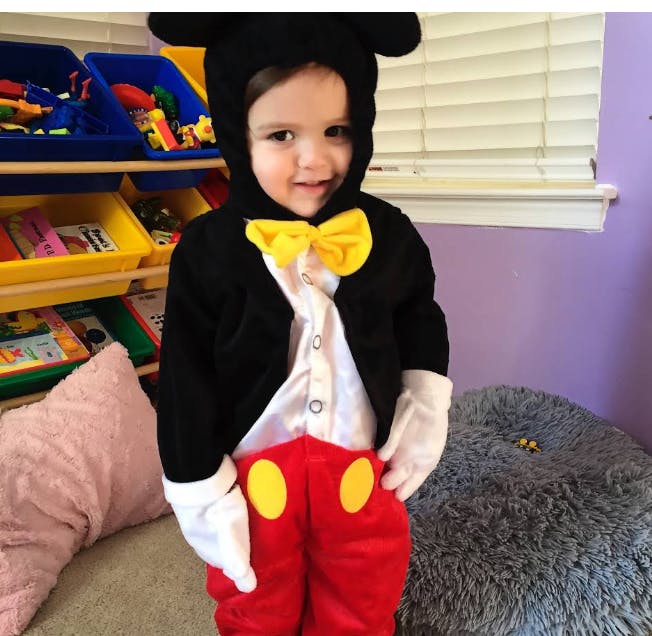 Child in a costume with a black top, red pants, and yellow bow tie