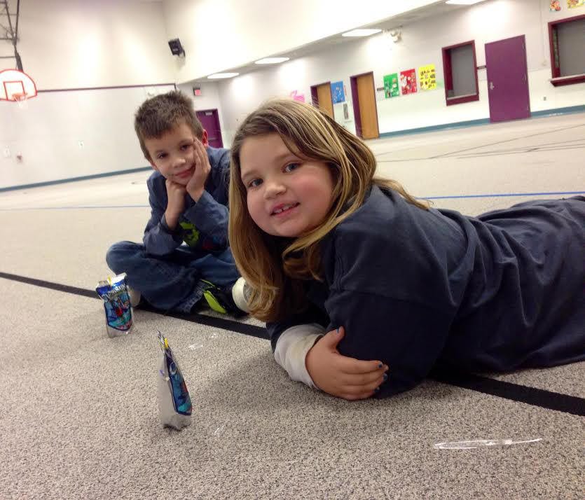 Child lying on floor looking at camera, another child sitting behind
