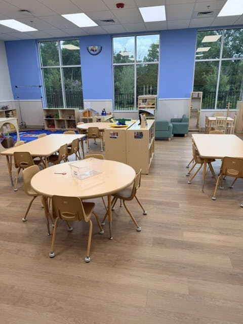 Empty preschool classroom with small tables and chairs