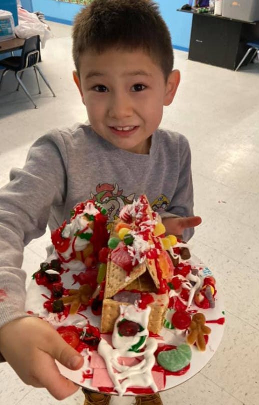 Child holding a decorated gingerbread house