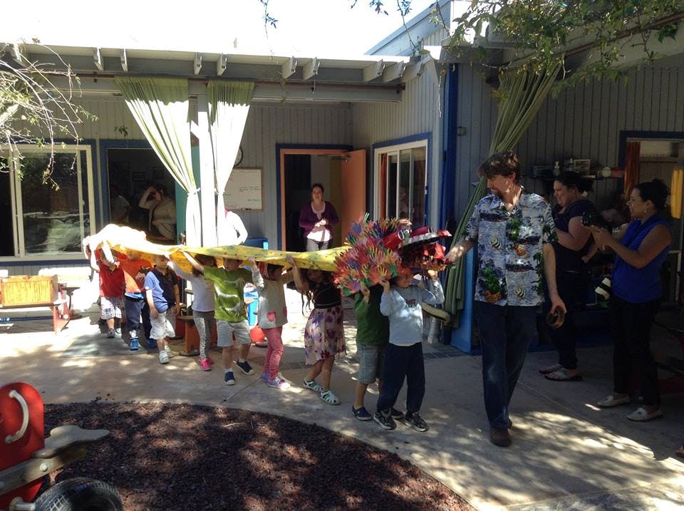 Children and adults carrying a long, colorful object outdoors