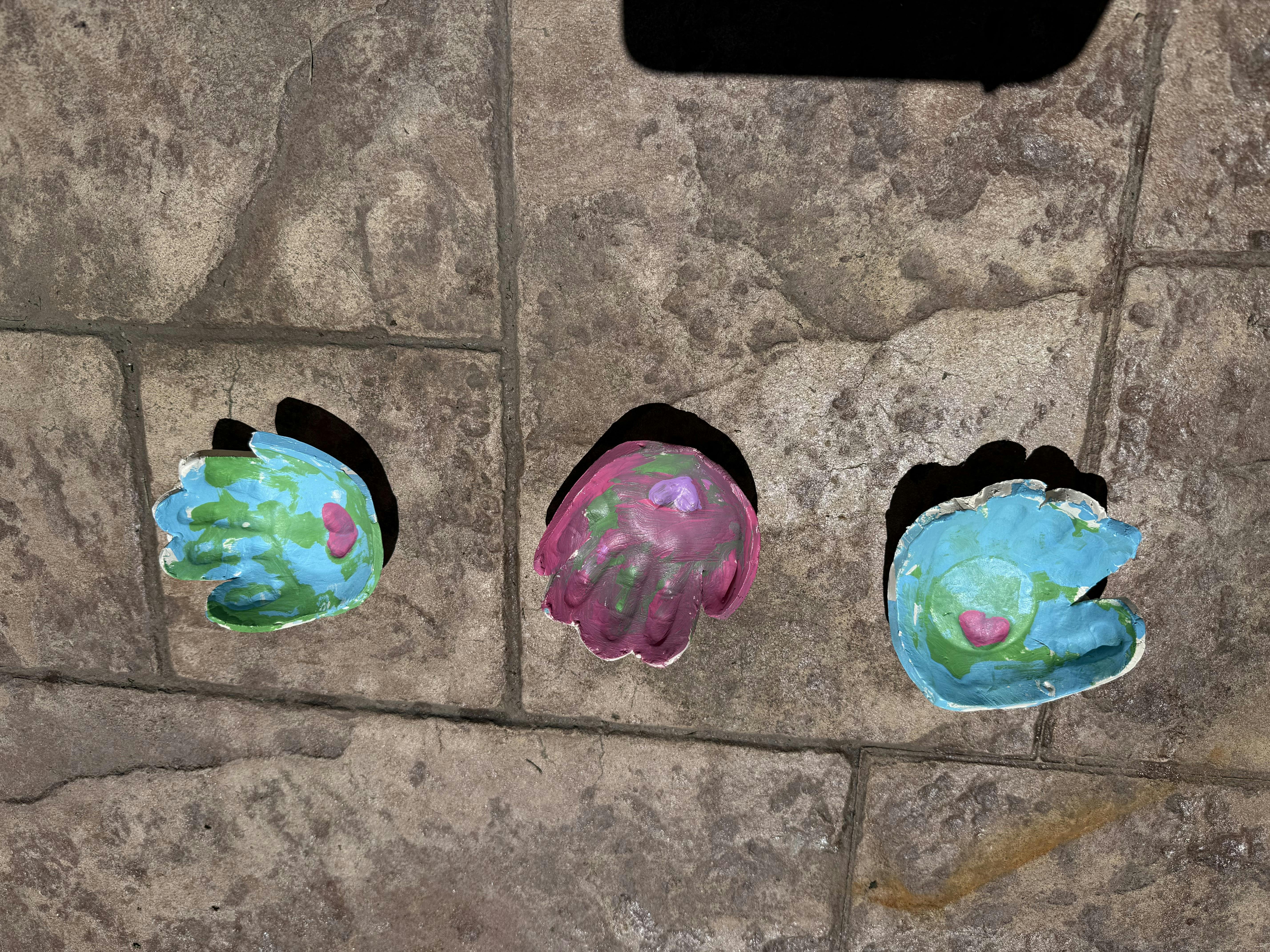 Three colorful handprint molds on a stone surface