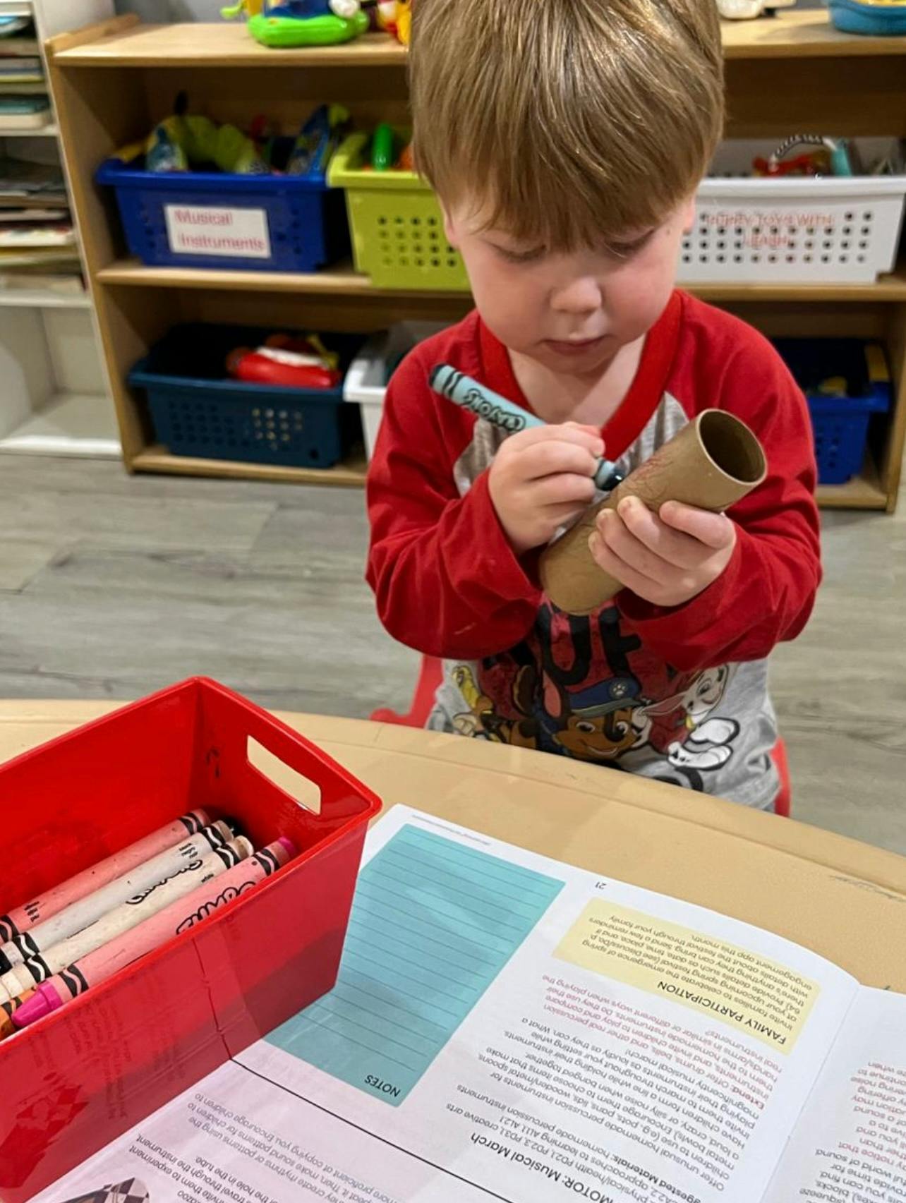 Child drawing on a cardboard tube with a crayon
