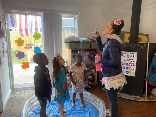 Person blowing bubbles for three children