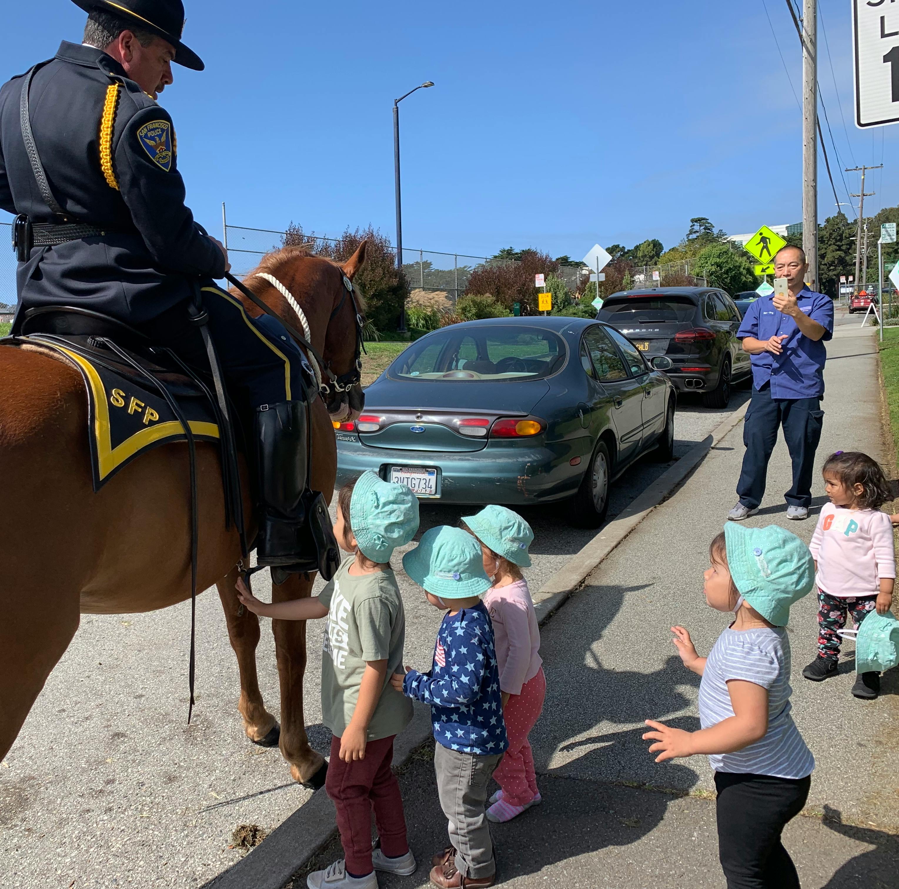 Person on horseback with children on a sidewalk