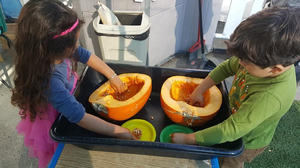 Two children scooping out pumpkins