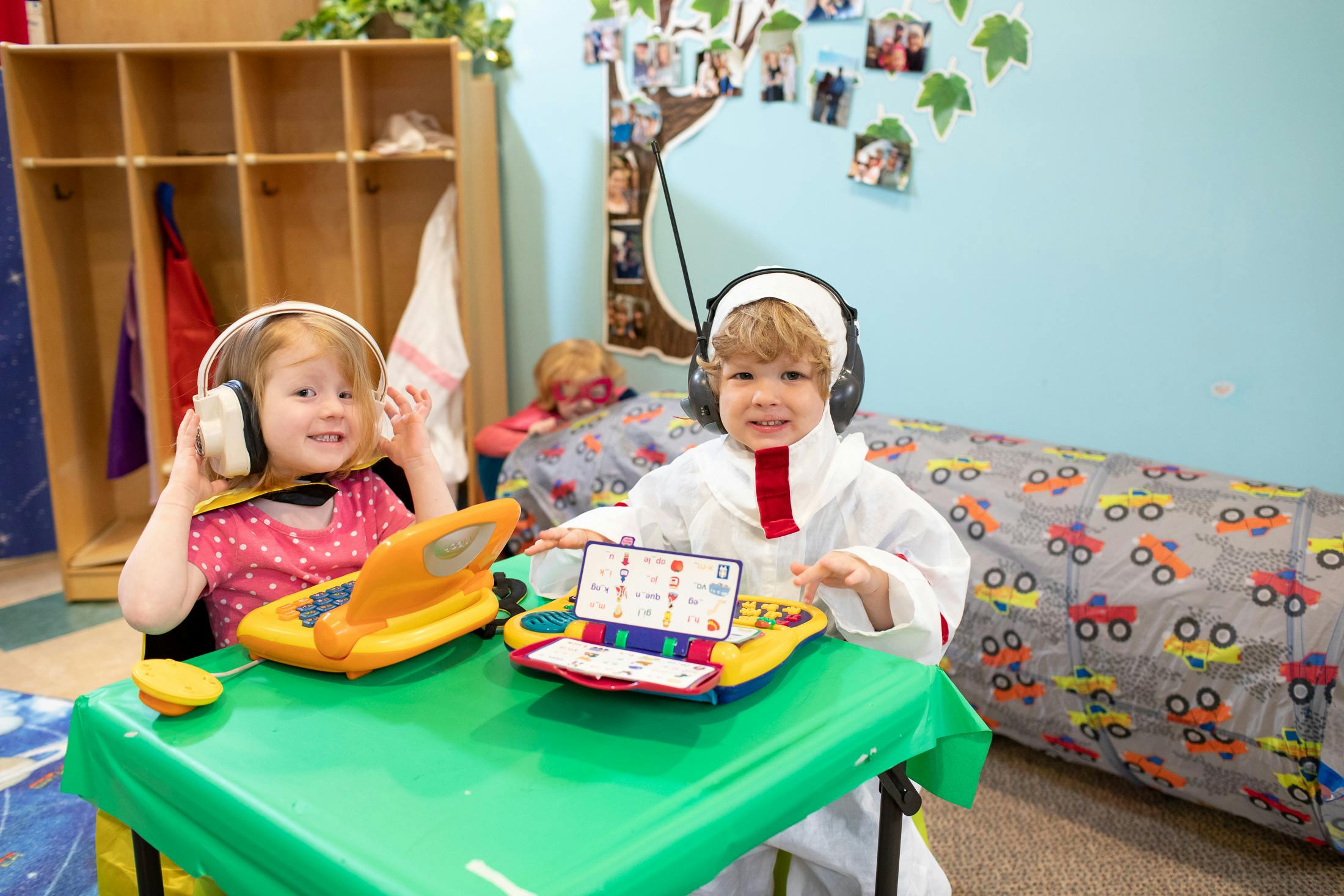 Two children wearing headphones and playing with learning toys at a table