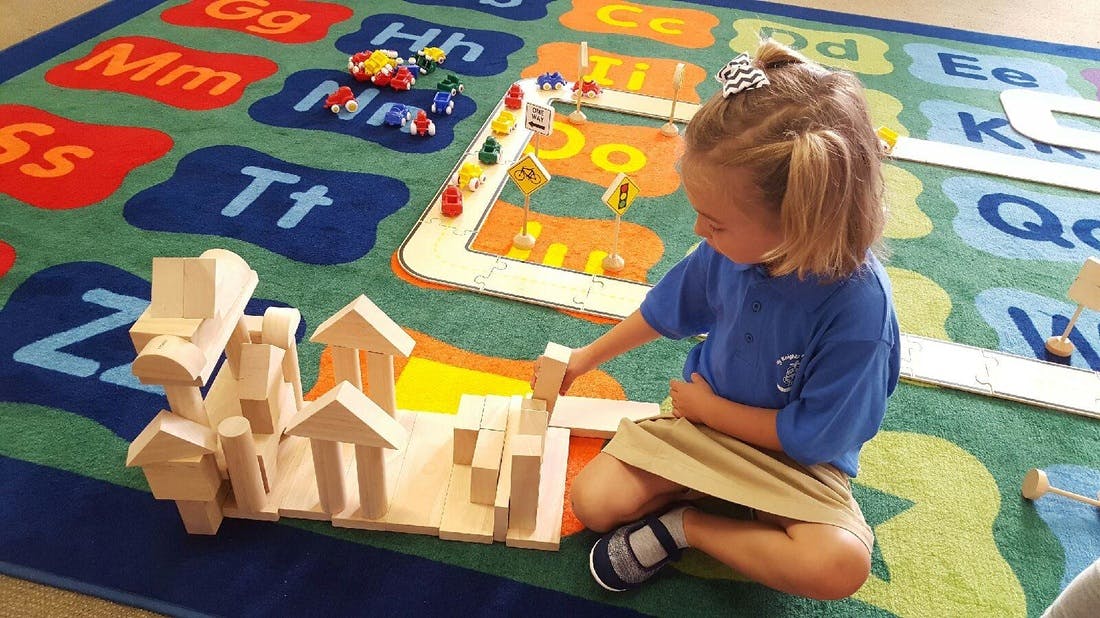 Child playing with wooden blocks on an alphabet rug