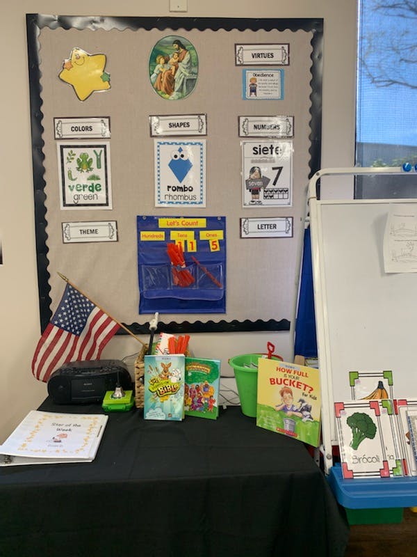 Classroom bulletin board with learning materials and a table with books