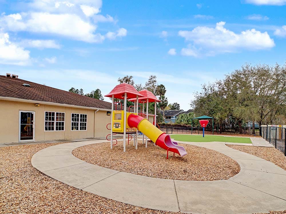 Playground with yellow and red slide structure next to a building