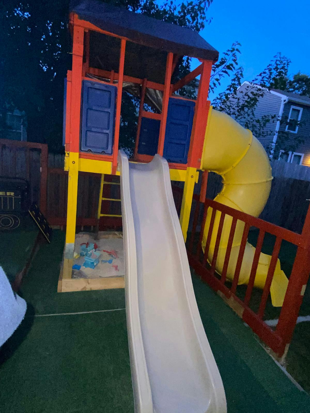 Wooden playground structure with a slide and a sandbox underneath
