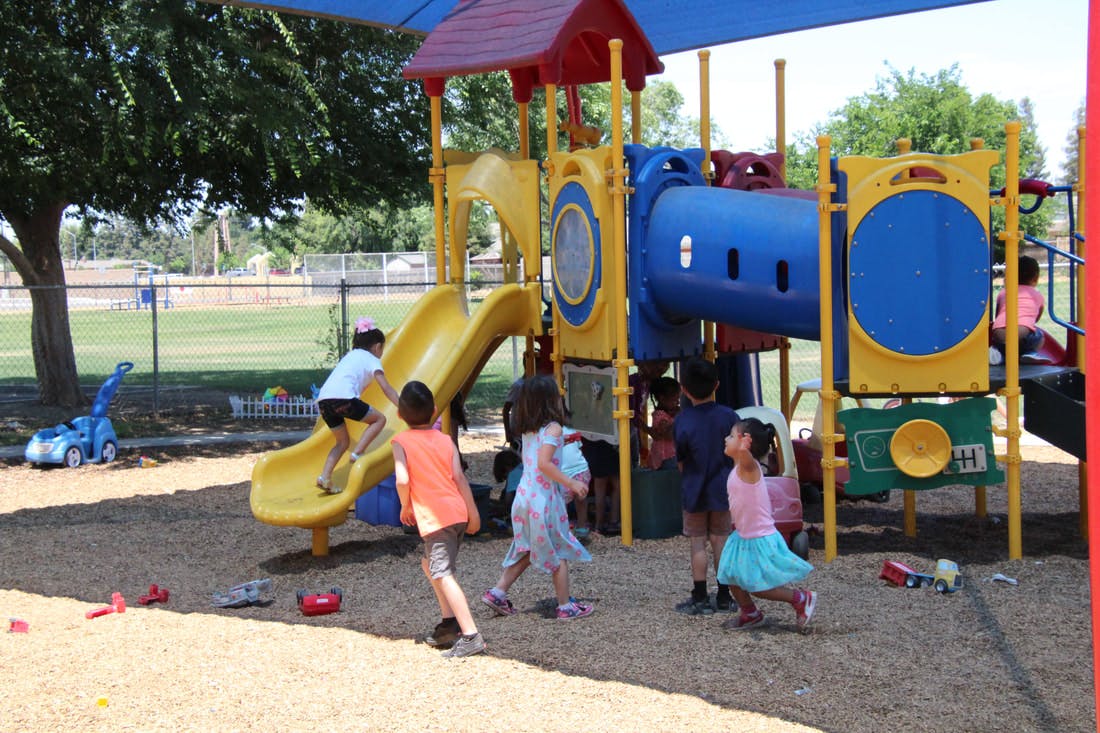 Children playing on a playground structure with slides and climbing structures