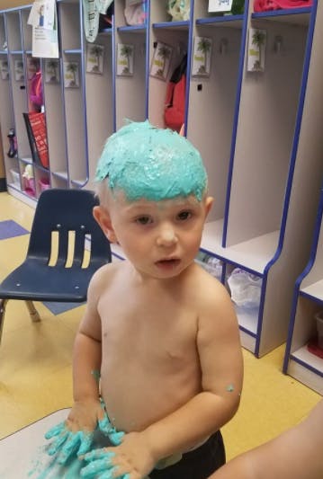 Child with blue substance on head and hands