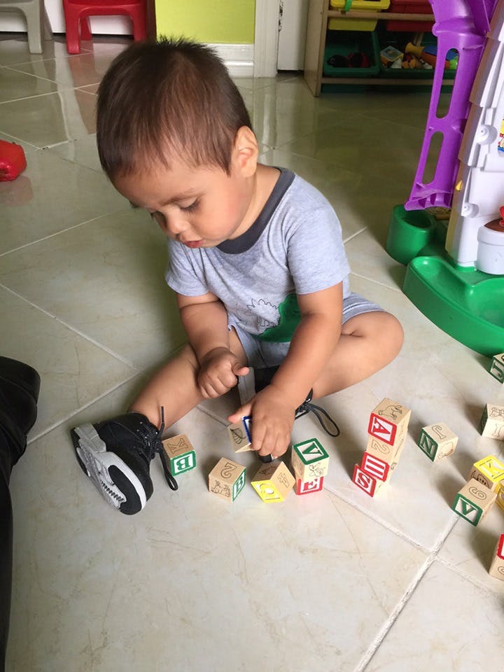 Child sitting on floor playing with alphabet blocks