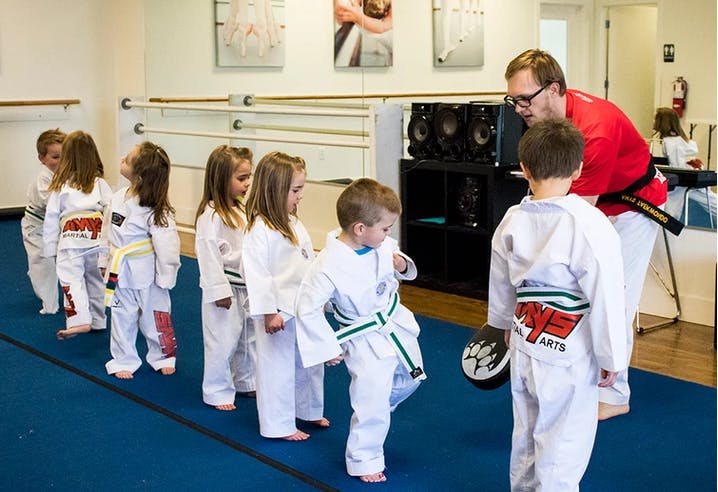 Adult teaching martial arts to a line of children in a studio
