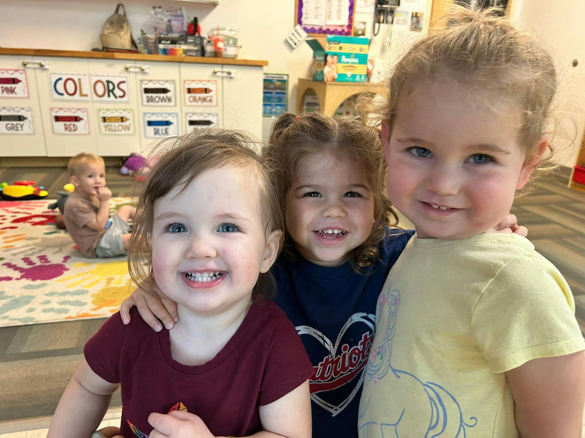 Three children smiling in a classroom