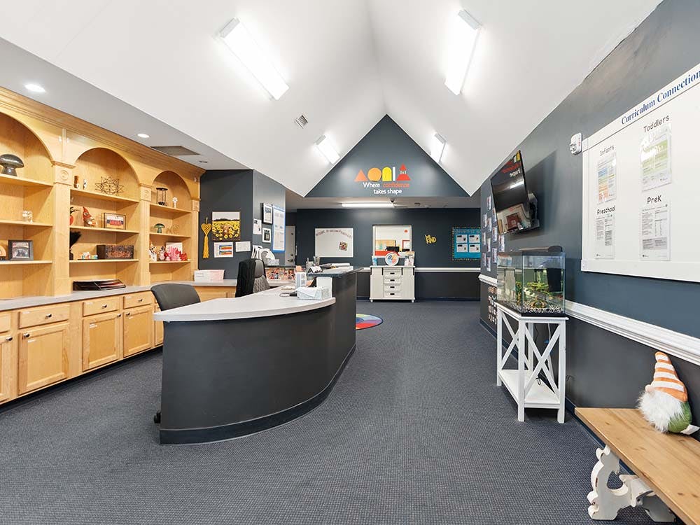 Reception area with a dark gray counter, wooden shelves, and an aquarium