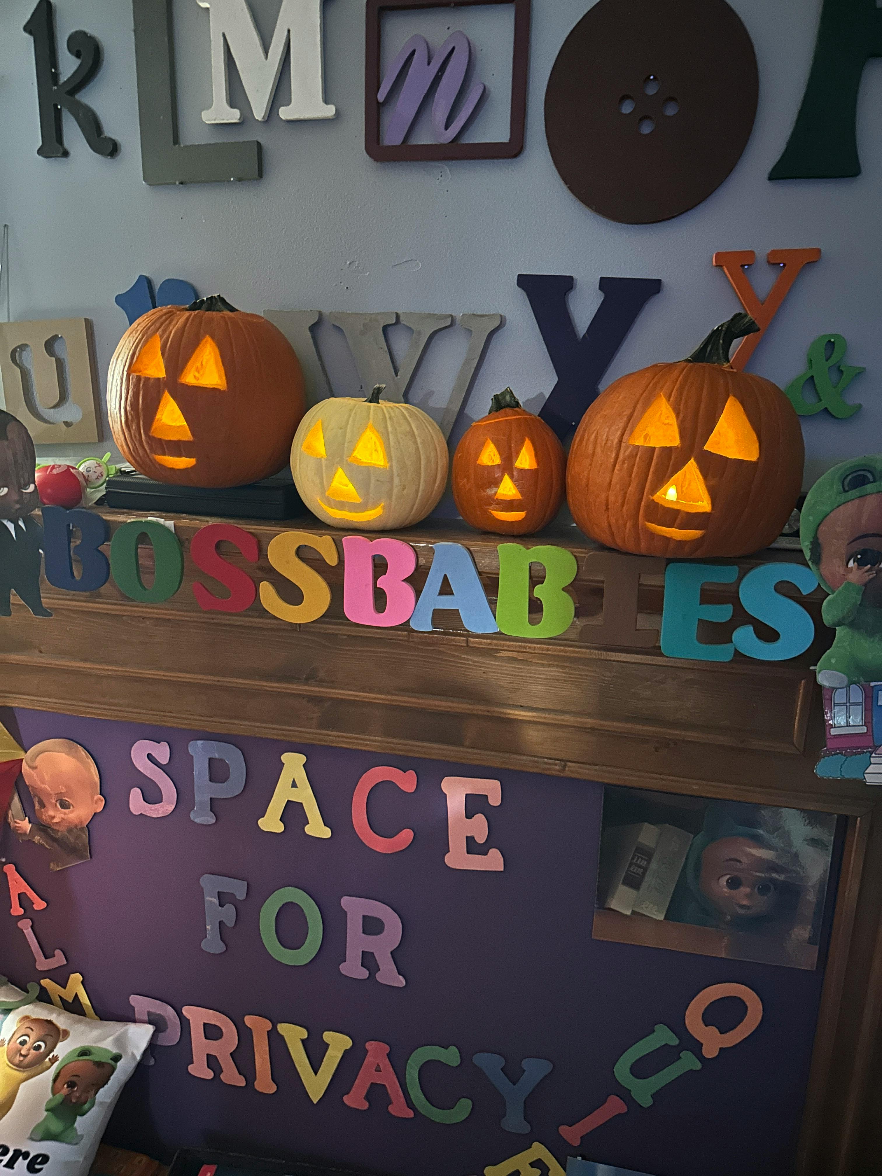 Four carved pumpkins with lights inside, with colorful letters below