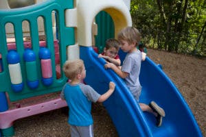 Three children playing on a slide