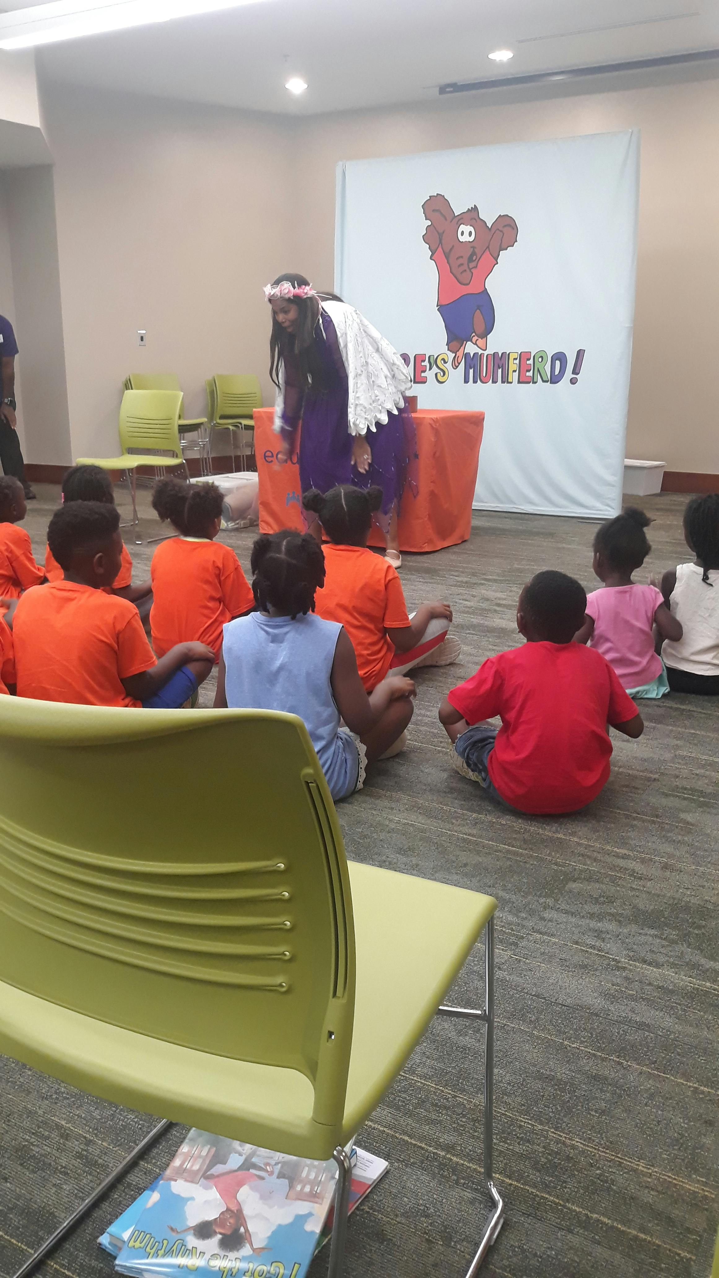 Person speaking to a group of children sitting on the floor